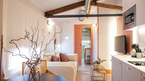 A modern living space with a sofa, a dining table, a kitchen area with a microwave, and a television.