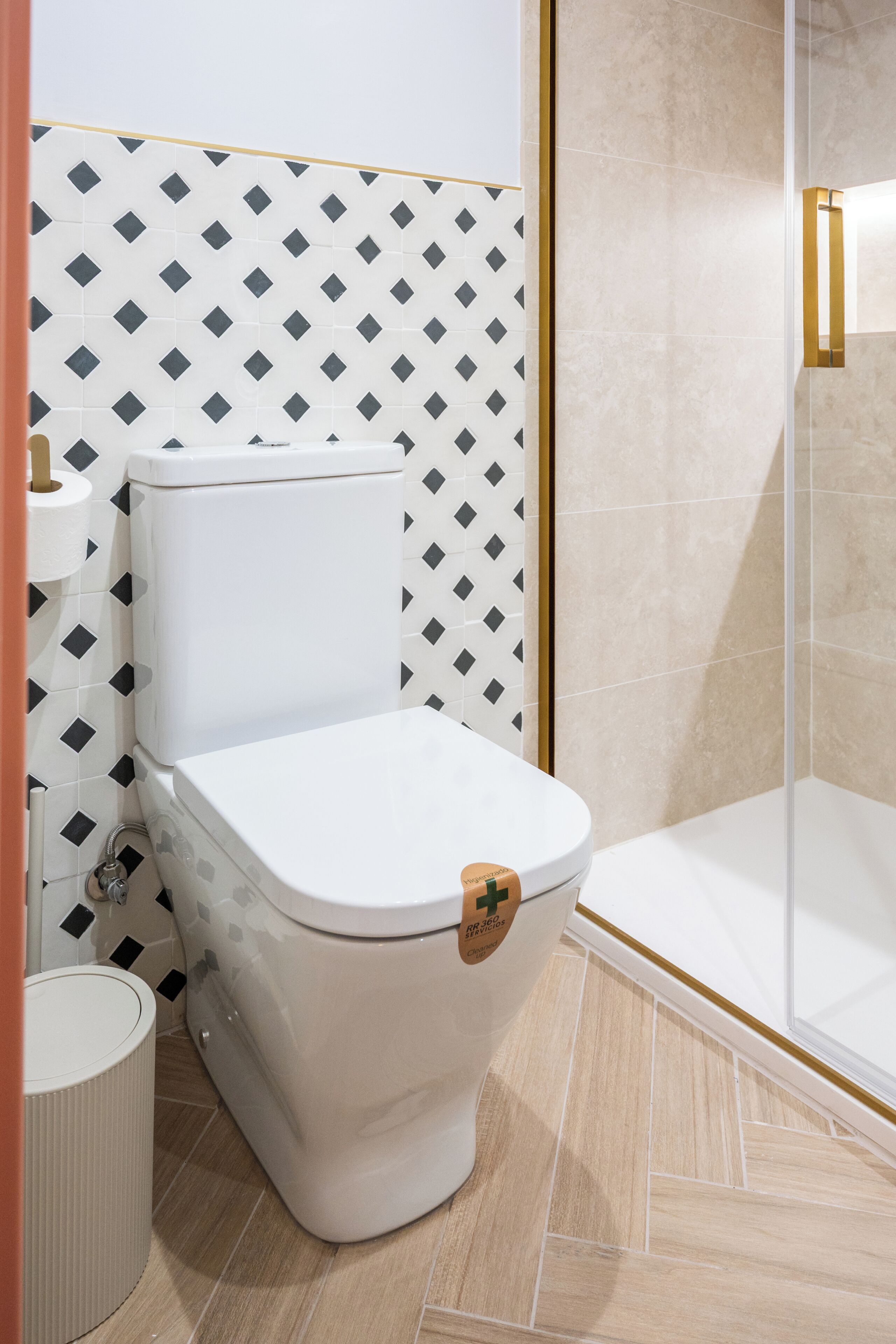 Une salle de bain avec des toilettes, une douche et un mur décoré d’un motif.