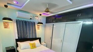 A bedroom with a bed, a desk, a chair, a wardrobe, and a ceiling fan. - Spacious 4-bedroom villa in pleasant Vijayawada with AC (VIJAYAWADA)