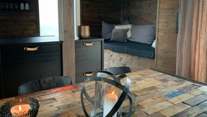 Ein gemütliches Zimmer mit Holzboden, einem Esstisch mit Kerzen, einer Couch und einer Bar mit Gläsern.