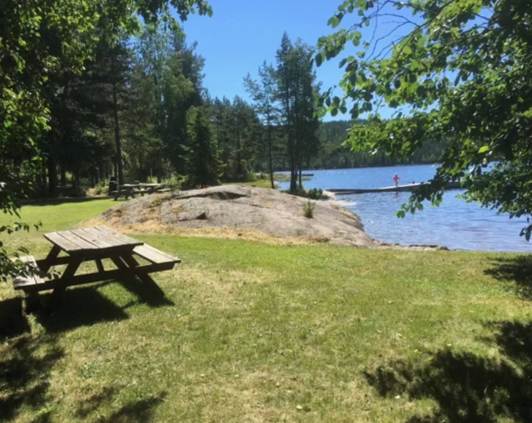 A picnic table, a rocky outcrop, and a lake.