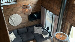 Ein modernes Wohnzimmer mit einer Eckcouch, einem Fernseher und hängenden Korblampen.