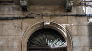 A brown double door with a decorative arch above it, set in a stone building. - 4Duques Apartments (Cáceres)