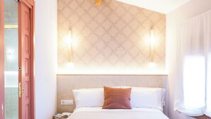 A hotel room with a bed, a nightstand, a wall-mounted light, and a door. - 4Duques Apartments (Cáceres)
