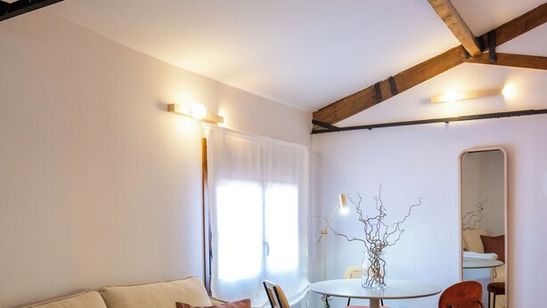 A living room with a sofa, a coffee table, a dining table with chairs, a mirror, and a window with curtains. - 4Duques Apartments (Cáceres)