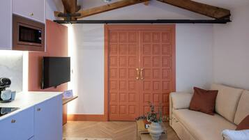 Ein gemütlicher Wohnraum mit Küchenzeile, Fernseher, Sofa und Holzboden.