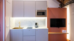 A modern kitchen with a built-in microwave, a sink, and a flat-screen TV mounted on the wall. - 4Duques Apartments (Cáceres)