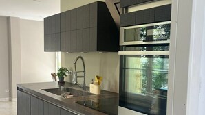 Una cocina moderna con armarios oscuros, un lavamanos de acero inoxidable y un horno empotrado.