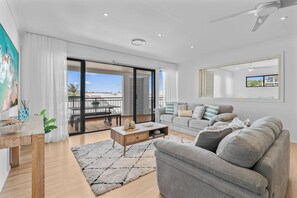 Ein modernes Wohnzimmer mit einer Couch, einem Couchtisch und Blick ins Freie.