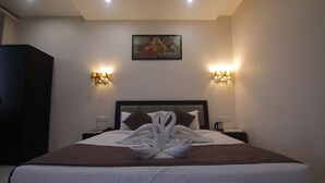 Una habitación de hotel con una cama bien hecha, un cuadro en la pared y lámparas fijadas a la pared.