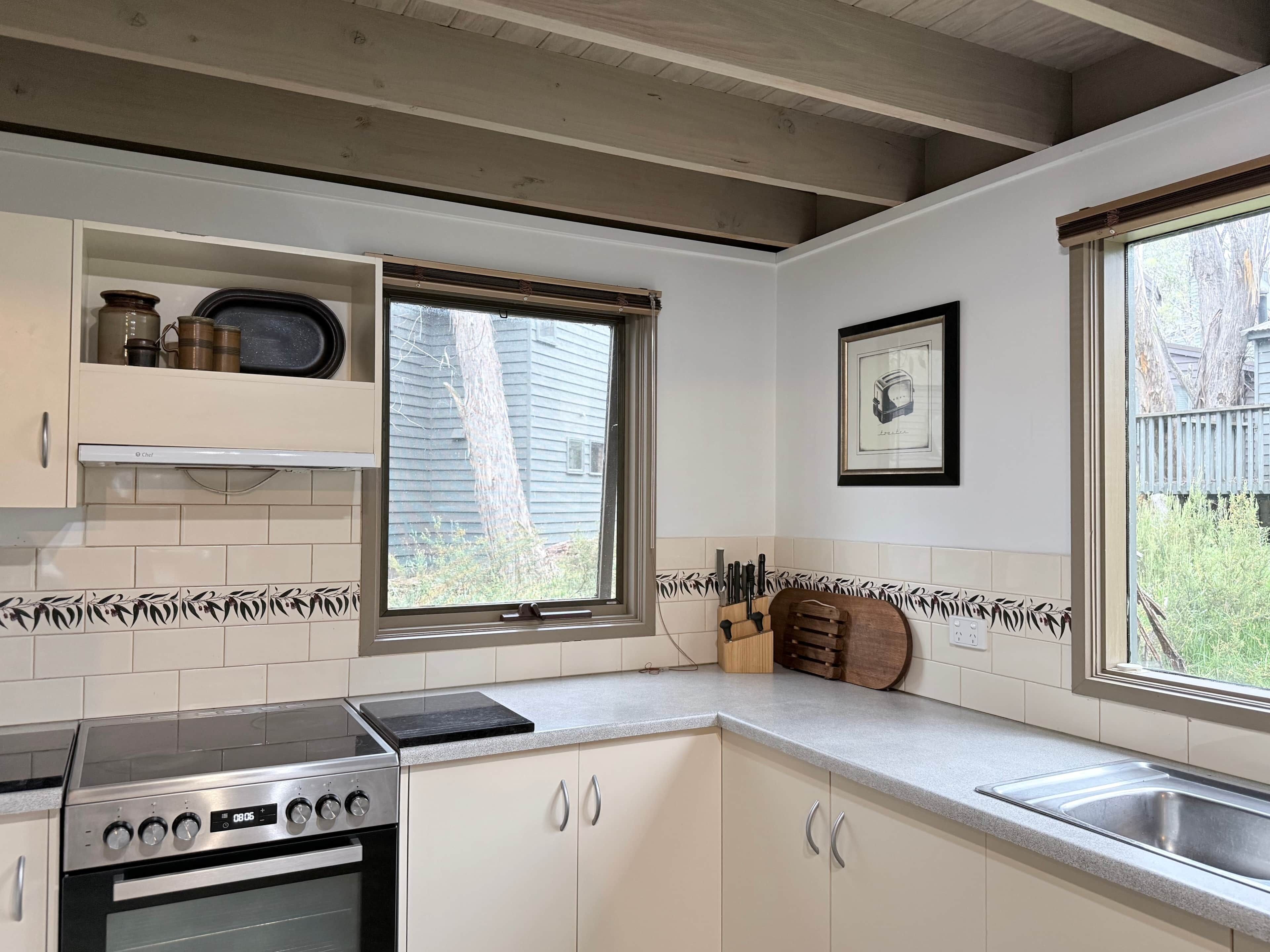 A kitchen with white cabinets, a stove, a window, and a knife block.