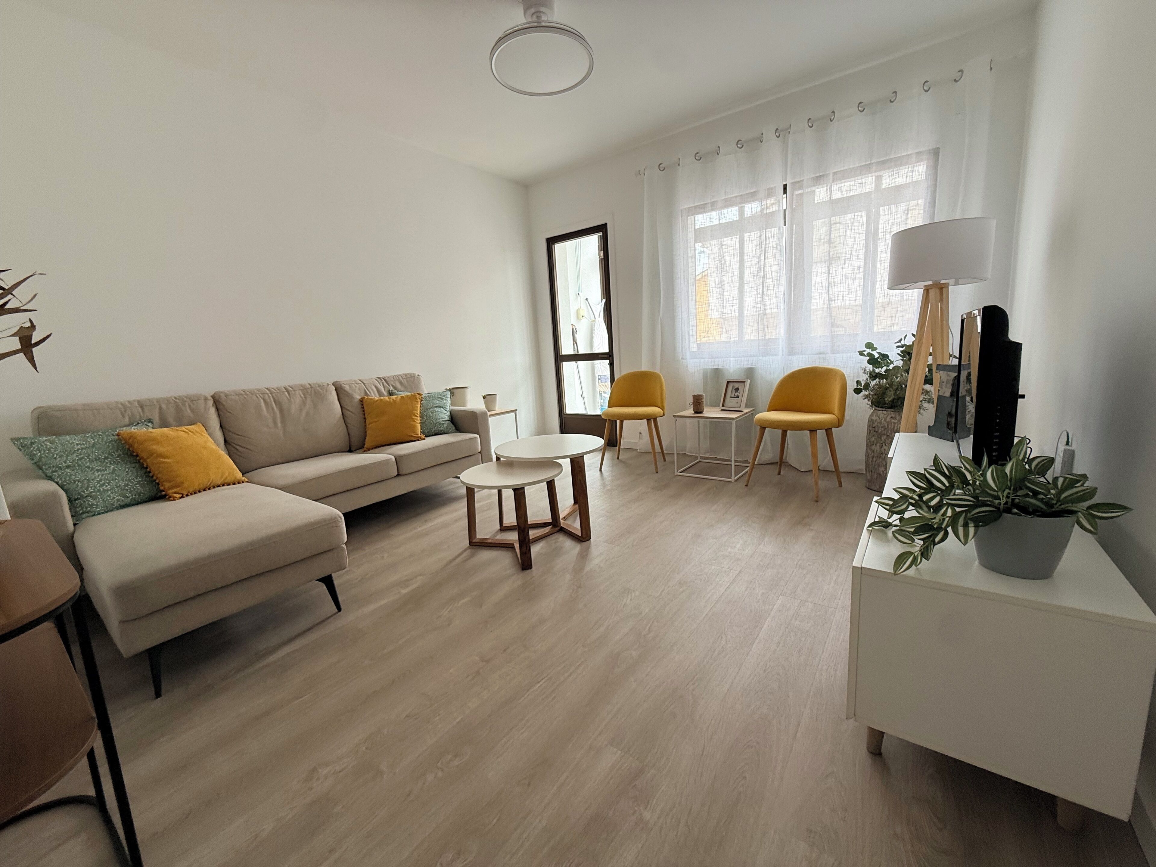 Una sala de estar moderna con un sofá, dos sillones, una mesa de centro y un mueble de televisión con una planta.