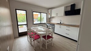 Una cucina moderna con mobili bianchi, un tavolo da pranzo con sedie e vista dalle finestre.