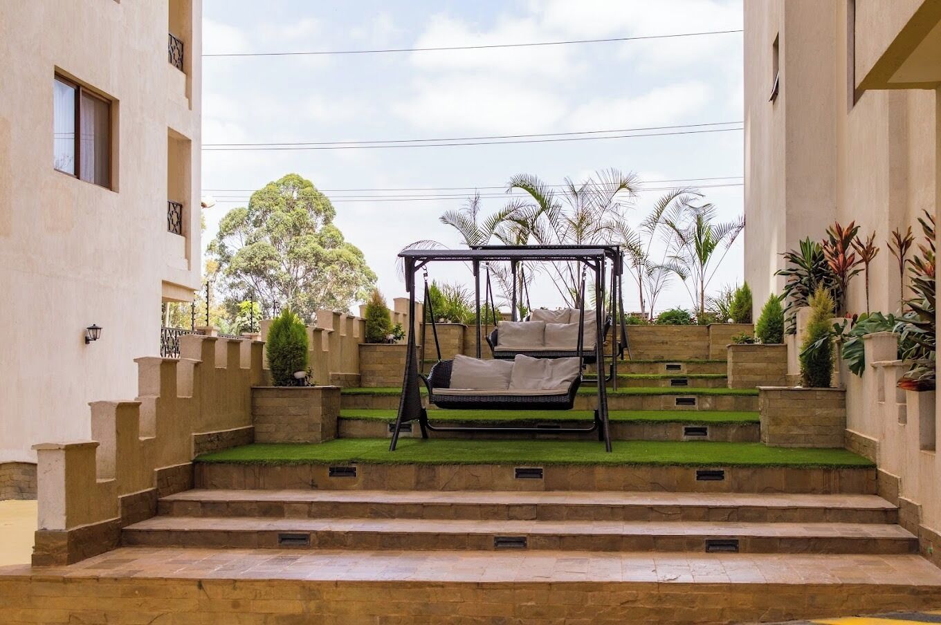 Un escalier extérieur menant à un espace jardin agrémenté d’une balançoire.