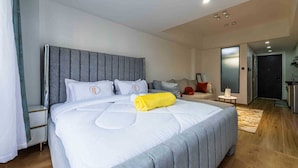 Et moderne hotelværelse med en stor seng, en sofa, et lille bord og en dør til et tekøkken.