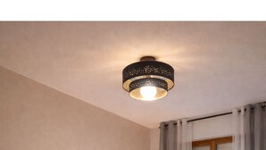 Ein Schlafzimmer mit Bett, Nachttischlampen, einem Schreibtisch, einem Fenster mit Vorhängen und einem gerahmten Bild an der Wand.