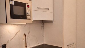 Eine moderne Küche mit integriertem Mikrowellenherd, Spüle aus Edelstahl und Marmorarbeitsplatte.