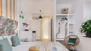 Une chambre d’hôtel avec un lit, une chaise, une armoire et une plante suspendue.