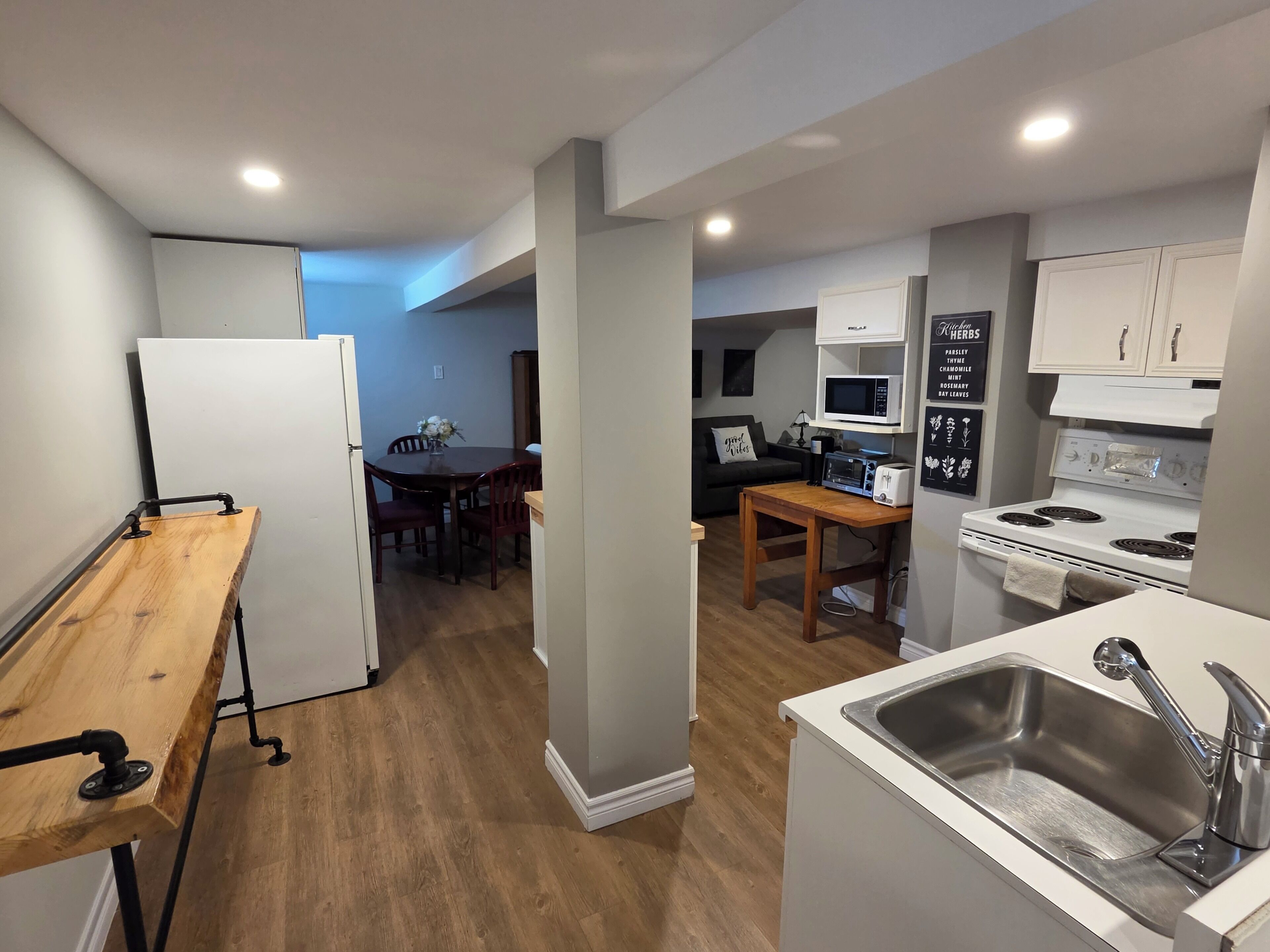 A compact kitchen with a wooden table, a built-in oven, and a white sink.