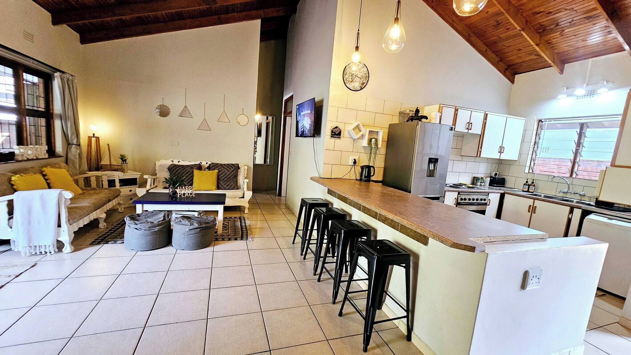 Une cuisine moderne dotée d’un îlot central, de tabourets de bar et d’un coin repas comprenant un canapé et une table basse.