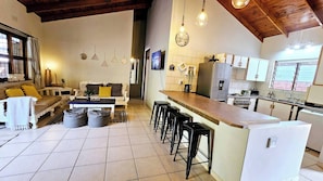 Une cuisine moderne dotée d’un îlot central, de tabourets de bar et d’un coin repas comprenant un canapé et une table basse.