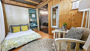 Une pièce confortable avec un lit, une chaise, une petite table et un miroir.
