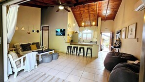 Un salon confortable avec un canapé, une petite table à manger et un coin cuisine équipé de tabourets.