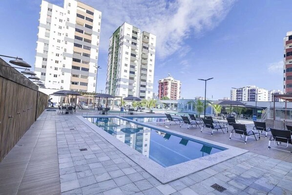 A rooftop pool area with lounge chairs and a clear view of surrounding high-rise buildings.