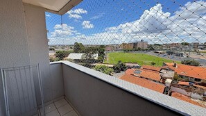 A balcony with a chain-link fence overlooking a sports field and buildings.