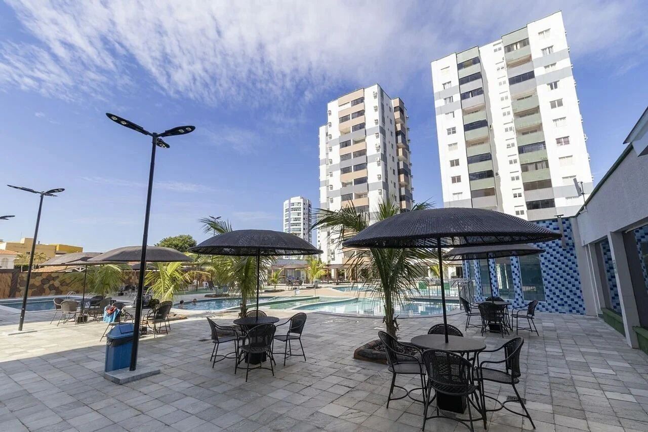 Zona de piscina en la azotea con mobiliario exterior y sombrillas, rodeada de altos edificios residenciales.