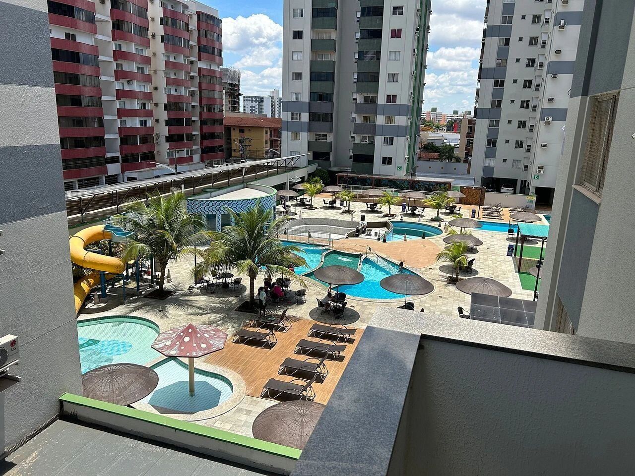 Un área de piscina en la azotea con varias piscinas, tumbonas y sombrillas.