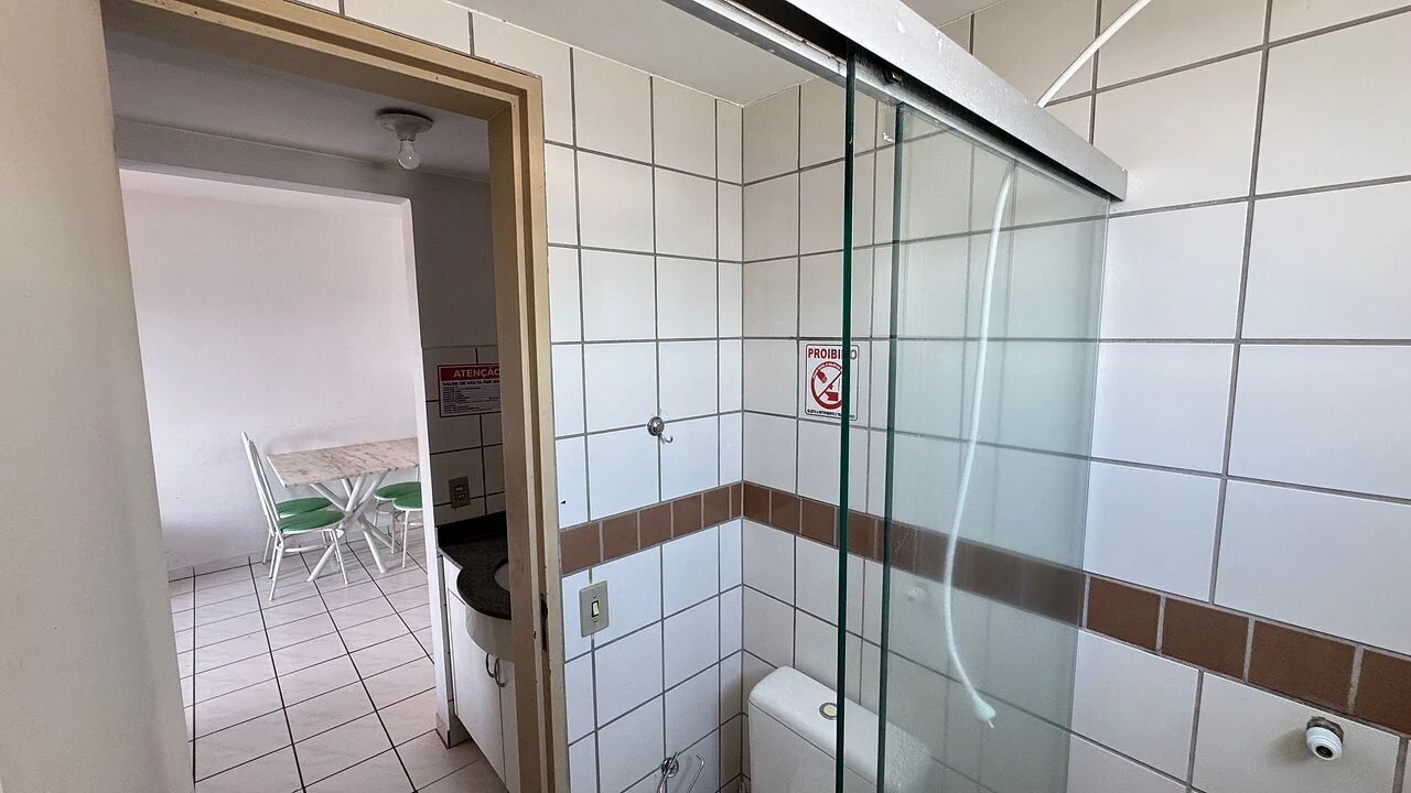 A bathroom with a glass shower enclosure, a toilet, and a sink.