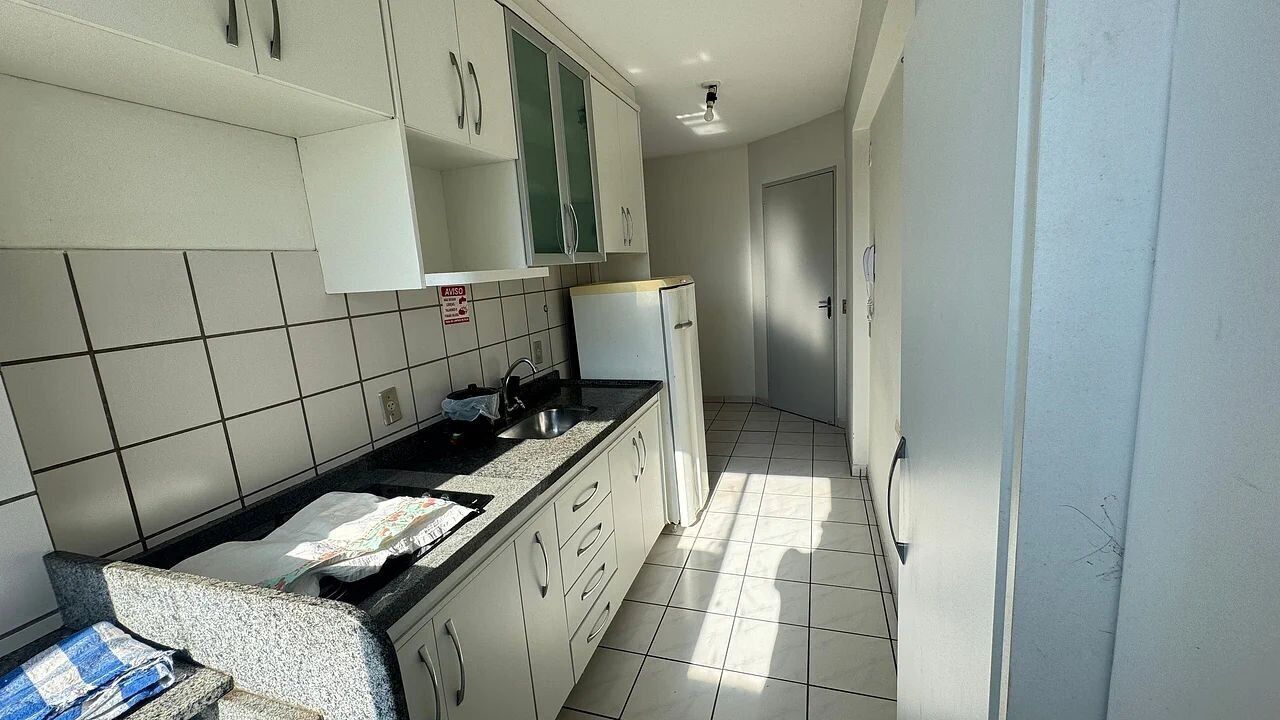 A kitchen with white cabinets, a black countertop, and a tiled floor.