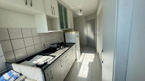 Ett kök med vita skåp, en svart bänkskiva och ett kaklat golv.