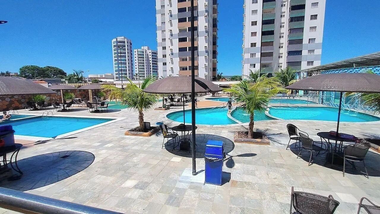 A hotel pool area with multiple pools, outdoor seating, and tall buildings in the background.