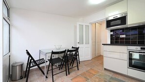 Una cucina moderna con mobili bianchi, un piano di lavoro nero e un'area pranzo con tavolo e sedie.