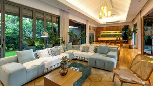 Una sala de estar moderna con un sofá modular, una mesa de centro y un comedor, con una cocina al fondo.