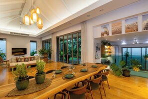 A spacious dining area with a long wooden table set for a meal, surrounded by chairs.