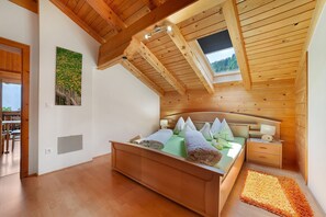 Un dormitorio con techo de madera, una cama, una mesita de noche, una lámpara de pared y una ventana.