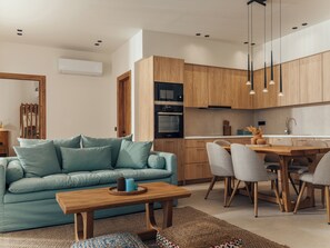 Ein modernes Wohnzimmer mit einer Couch, einem Holztisch und einem Essbereich mit Stühlen und Tisch.