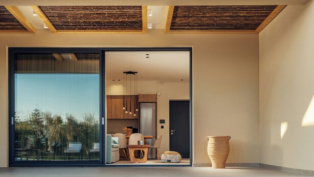 Un interior modern amb una piscina de vidre, una zona de menjador i una cuina visibles a través de les portes de vidre.