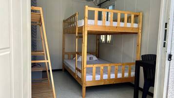 Dormitorio con literas, una escalera, una silla y un equipo de aire acondicionado.
