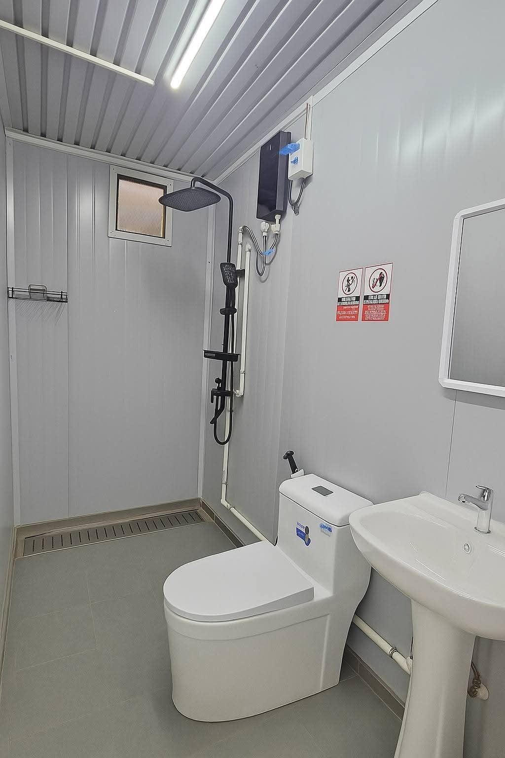 Une salle de bain équipée de toilettes, d’un lavabo, d’une douche et d’un miroir.
