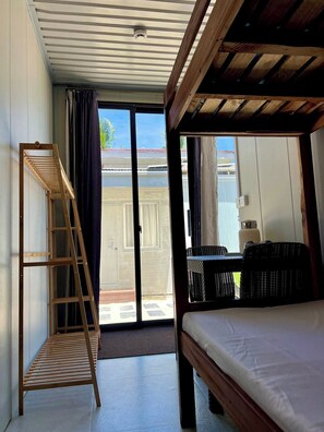 A room with a bed, a wooden ladder, a sliding glass door, and wicker furniture. - Crossa Inn Siquijor (Siquijor)