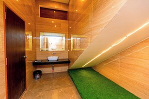 A bathroom with a vanity, sink, mirror, and a green artificial grass area. - T Resort (Vanur)