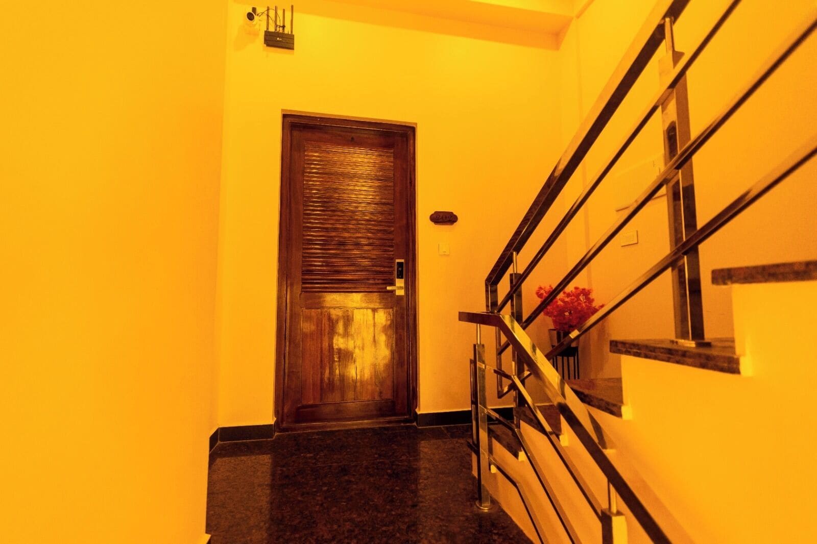 A hallway with a wooden door and a metal staircase.