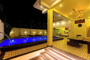 A pool area with a water feature, a staircase, and a room with a bed and a dining area. - T Resort (Vanur)
