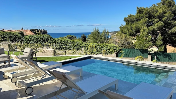 Una piscina con lettini, vista sul mare e un muro in pietra.