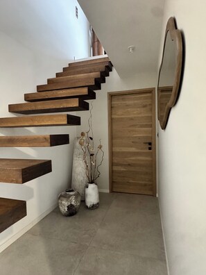 Eine Treppe mit Holzbalken, ein Spiegel und zwei Vasen auf dem Boden.