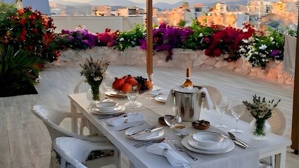 Un espace de restauration en plein air avec une table dressée pour quatre personnes, entourée de chaises en osier blanc.